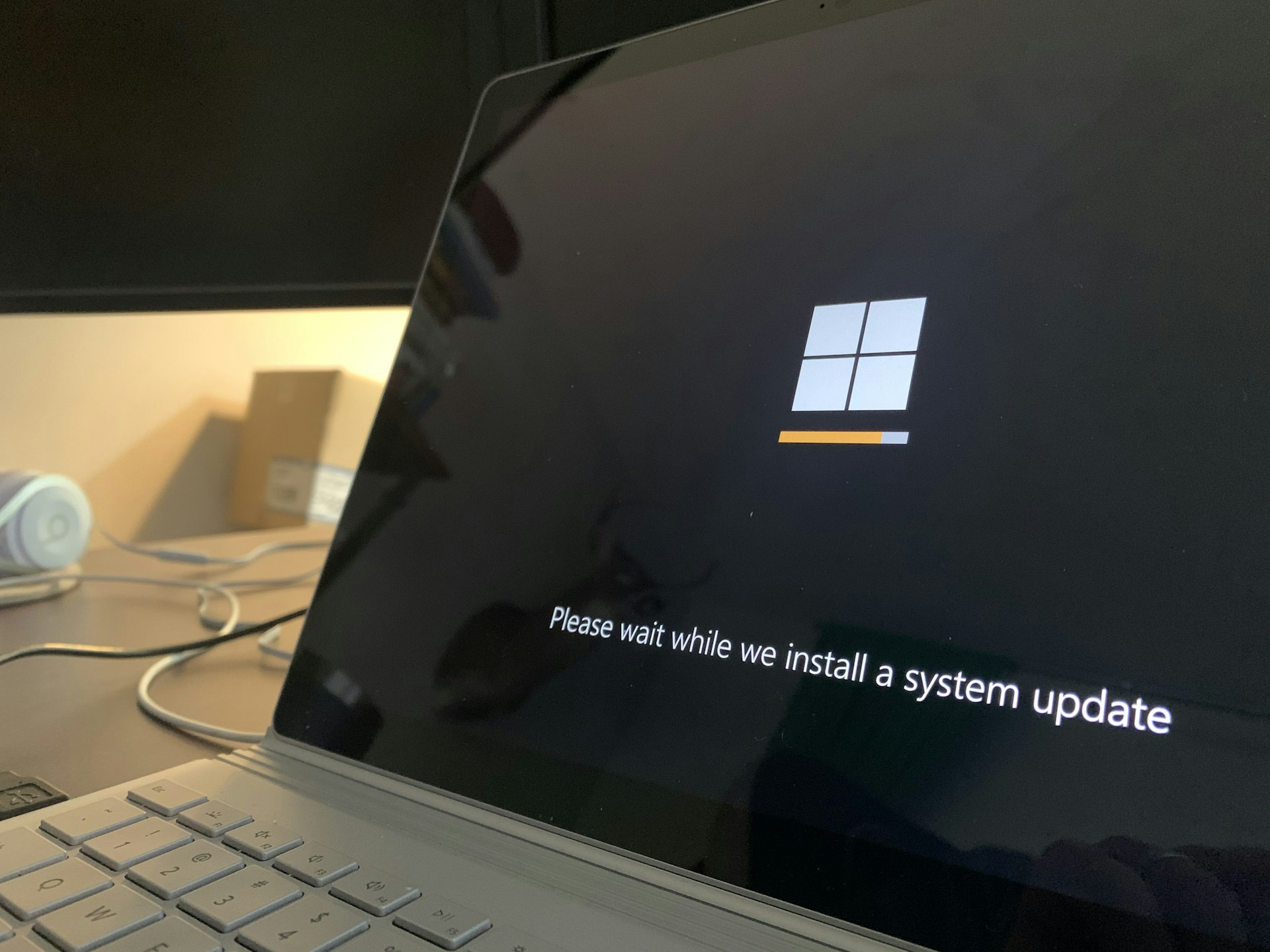 A laptop screen showing the Windows logo and the message "Please wait while we install a system update."