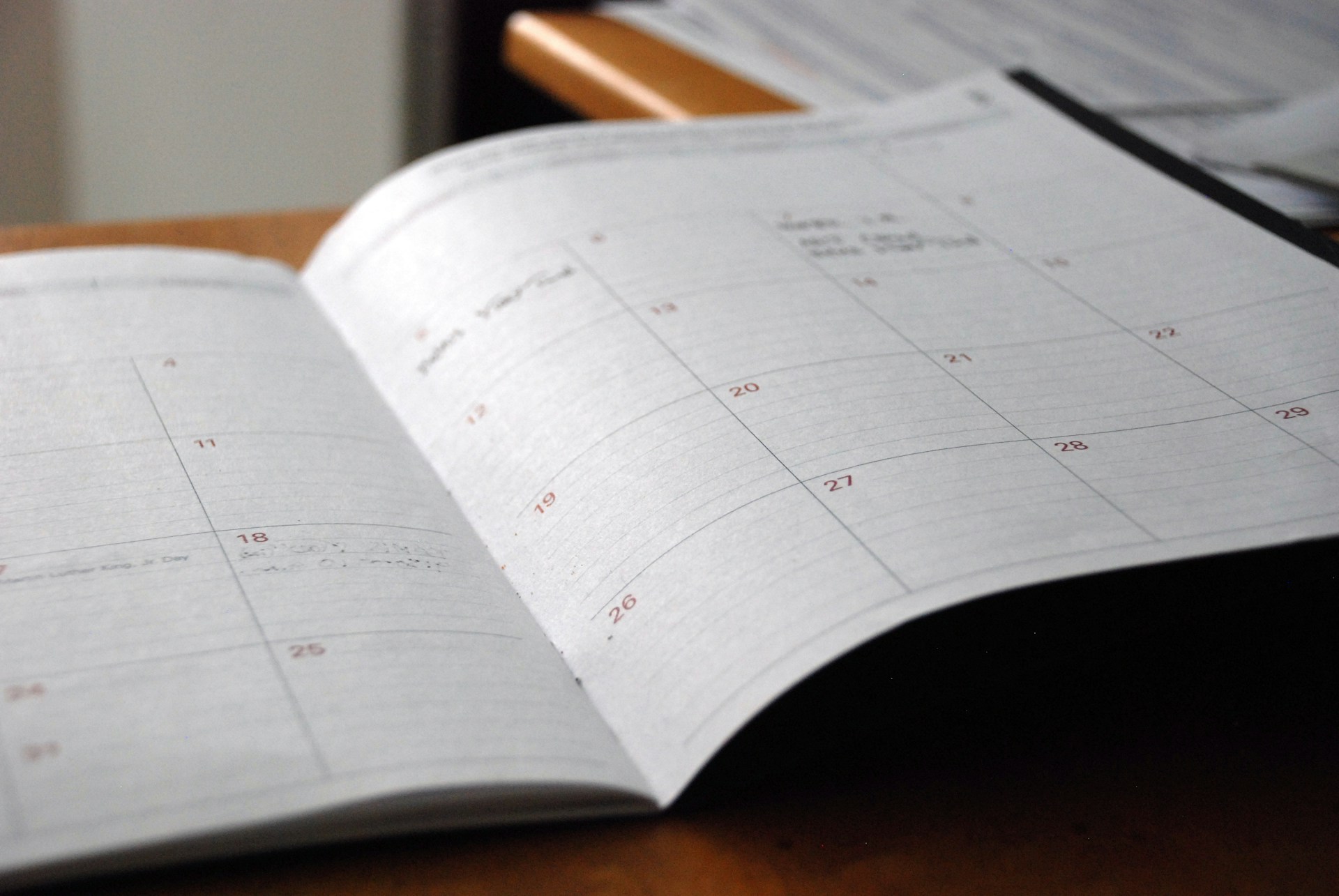An open monthly planner with a blank calendar grid on a desk.