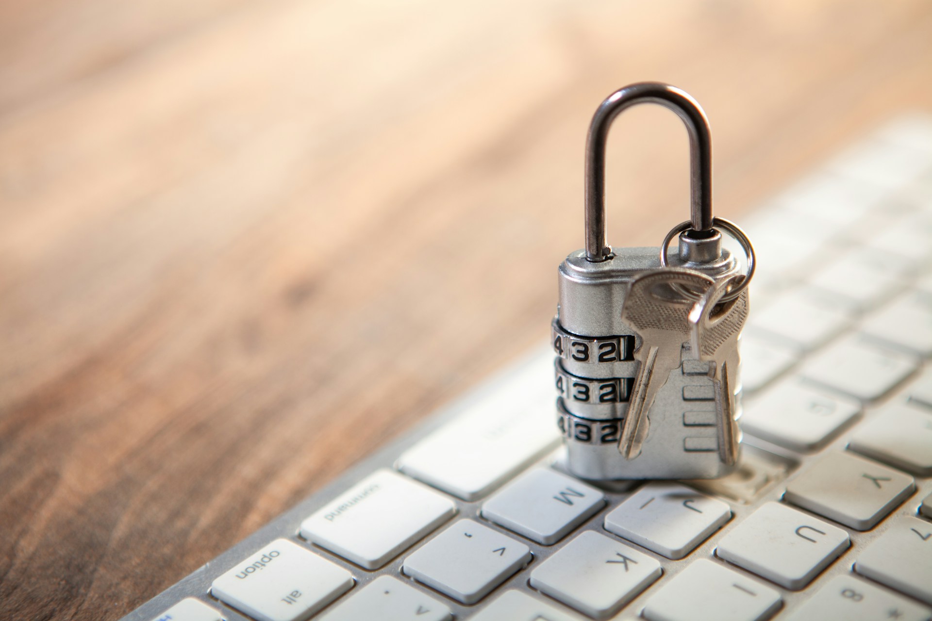 A combination padlock and keys resting on a computer keyboard.
