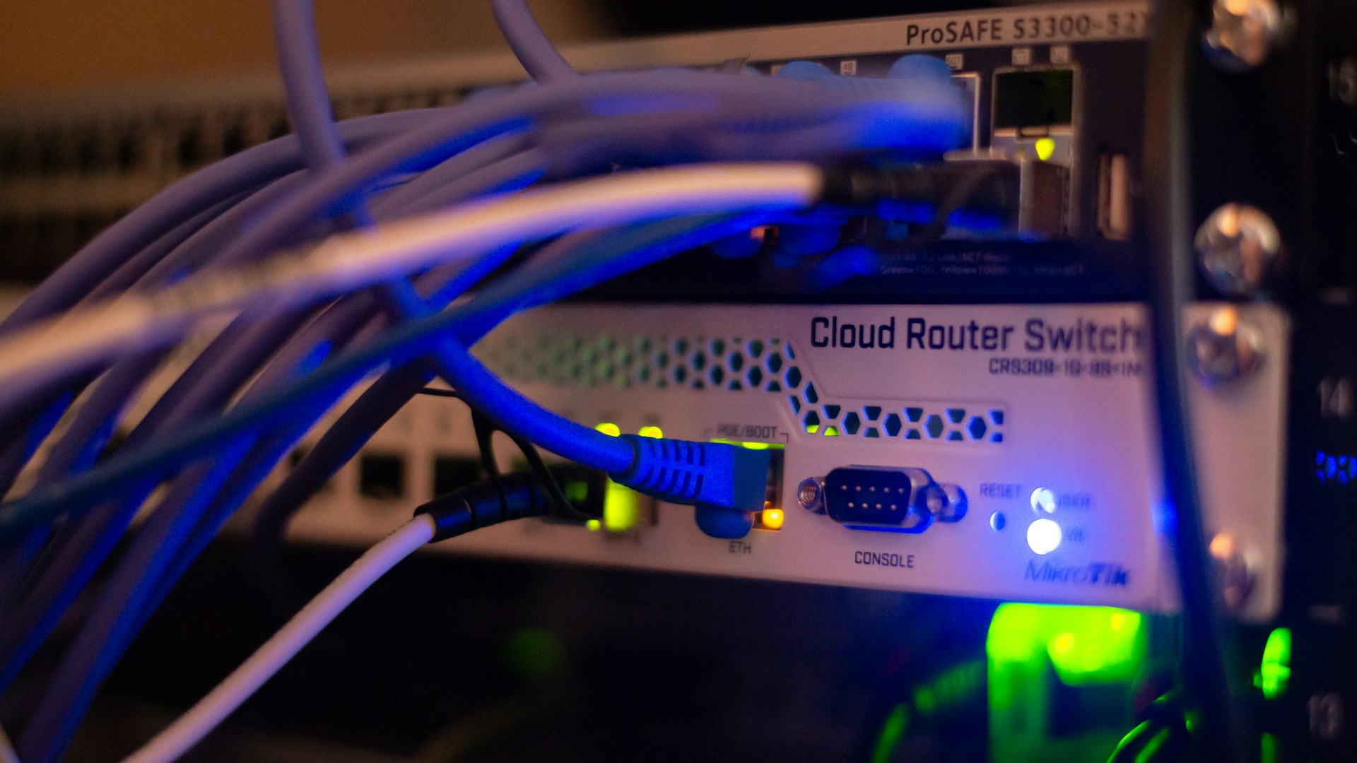 Ethernet cables connected to rack-mounted network switches with illuminated status lights.
